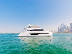 A stunning yacht glides through clear waters, showcasing its sleek design against a backdrop of modern skyscrapers — perfect for luxury cruising in vibrant cityscapes.