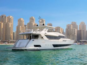 A stunning yacht is docked in clear waters with a backdrop of modern skyscrapers, showcasing luxury and elegance in a vibrant coastal setting.
