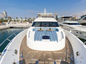 A stunning view of a yacht's front deck, showcasing stylish seating and a polished wooden finish, perfect for relaxing at the marina.