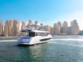 A stunning yacht glides through the waters with a backdrop of towering skyscrapers, showcasing luxury and elegance on the water.