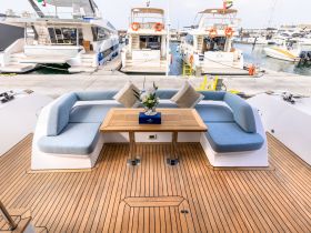 A beautifully designed lounge area inside a yacht, featuring comfortable seating and a stylish table, perfect for relaxing while enjoying the views at the marina.