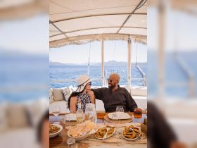 A couple enjoys a romantic dining experience on a yacht, surrounded by delicious food and stunning ocean views — perfect for special occasions or intimate getaways.