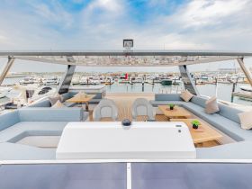 A spacious and stylish interior of a yacht featuring comfortable seating and a dining area, perfect for relaxing and entertaining while enjoying views of the marina.