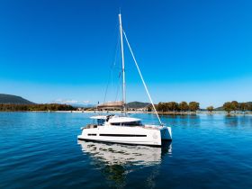 A stunning aerial view of a sleek catamaran gliding through calm waters, surrounded by picturesque landscapes — perfect for exploring coastal destinations.