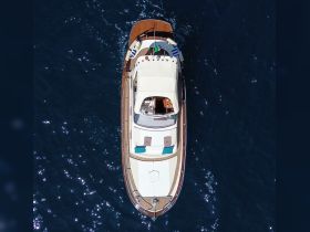 Aerial view of a sleek yacht gliding through deep blue waters, showcasing its elegant design and spacious deck — perfect for luxury outings on the sea.
