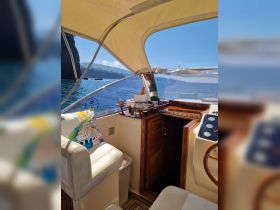A cozy interior view of a boat's helm and seating area, showcasing a comfortable space for navigating and relaxing while enjoying scenic views.