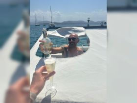 A joyful moment aboard a boat as a man raises a bottle while toasting with a glass of bubbly, perfect for celebrating special occasions on the water.