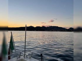 A serene sunset view from the bow of a boat, showcasing calm waters and distant mountains — perfect for tranquil evening cruises.
