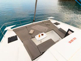 A cozy lounge area on a boat featuring comfortable seating and a small table, perfect for relaxing while enjoying the serene waters.