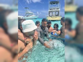 A lively group enjoys a fun day in the water near the 'Magic Hook' boat, creating unforgettable memories in the beautiful turquoise waters.