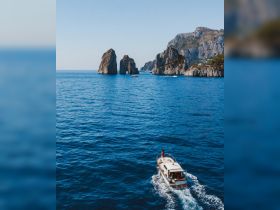 A scenic view of a boat cruising near iconic rock formations in crystal-clear waters, perfect for exploring the stunning coastline.