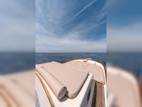 A serene view of the spacious deck of a yacht, showcasing comfortable lounging areas against a backdrop of calm waters and a clear sky — perfect for relaxation on the open sea.