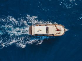 Aerial view of a group enjoying a day on a boat, sunbathing and cruising through vibrant blue waters — perfect for summer adventures and relaxation.