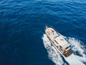 Aerial view of a boat cruising through deep blue waters with guests enjoying the ride — perfect for adventure seekers and group outings on the sea.
