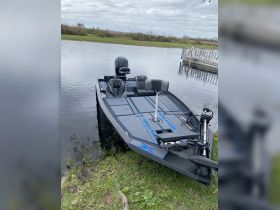 A sleek fishing boat is docked by the water's edge, showcasing its modern design and features — perfect for anglers seeking adventure.