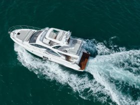 A stunning aerial view of a sleek yacht cruising through vibrant turquoise waters, showcasing its elegant design and smooth movement.
