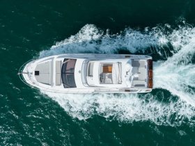 Aerial view of a sleek yacht cruising through vibrant turquoise waters, showcasing its elegant design and smooth movement.