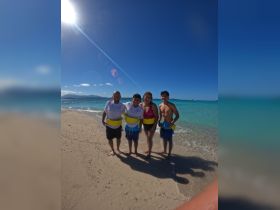 A joyful group poses on the beach, ready for a fun day in the water, showcasing the perfect family adventure in a tropical paradise.
