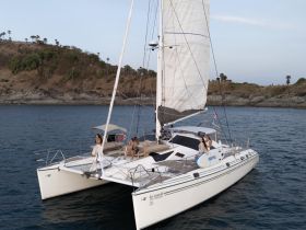 A group of friends enjoys a relaxing day aboard a catamaran, surrounded by stunning coastal scenery — perfect for celebrations and memorable outings on the water.