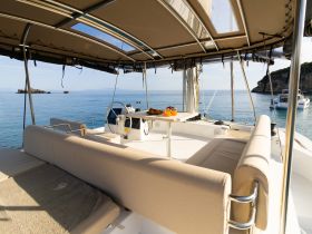 A serene view of the interior seating area on a yacht, featuring a comfortable lounge space and helm, perfect for relaxing while enjoying the tranquil waters.