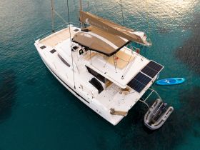 A stunning aerial view of the 'Crystal Sea' catamaran anchored in clear turquoise waters, showcasing its sleek design and solar panels.