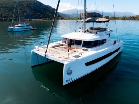 A stunning aerial view of a Bali catamaran docked in calm waters, surrounded by lush greenery and mountains — perfect for serene sailing adventures.