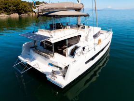 A stunning aerial view of a sleek catamaran docked in calm waters, showcasing its modern design and solar panels — perfect for eco-friendly sailing adventures.