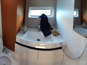 A clean and modern bathroom interior on a boat, featuring a sink, storage, and decorative shells — perfect for ensuring comfort during your nautical adventures.