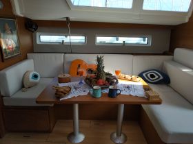 A beautifully arranged dining area inside a boat, featuring a selection of fruits, snacks, and drinks, perfect for a cozy gathering on the water.
