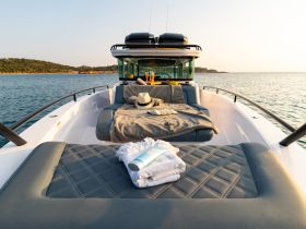 A beautifully arranged lounge area on a boat, featuring cozy blankets and towels, perfect for relaxing on the water.