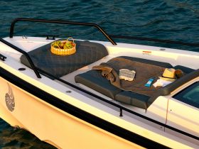 A cozy setup on a boat featuring a basket of fresh fruits, a towel, and a hat, perfect for a relaxing day on the water.