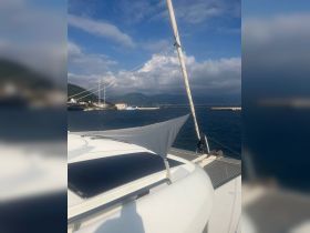 A serene view of a catamaran's deck with solar panels, showcasing the tranquil harbor and mountainous backdrop — perfect for sailing enthusiasts.