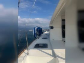 A clear view of the side deck of a yacht, showcasing its sleek design and tranquil waters in the background — perfect for a relaxing day on the water.