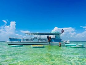 Guests enjoy a fun day on the water with Sandy Bottom Boat Tours, featuring swimming and relaxation around the boat in clear turquoise waters.