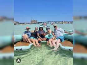 A lively group enjoys a fun day on the water, relaxing on a pontoon in shallow waters — perfect for summer gatherings and beach outings.