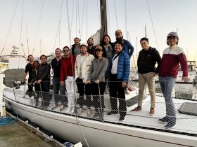 A cheerful group poses together on the deck of a sailboat, capturing a memorable moment of friendship and celebration at the marina.