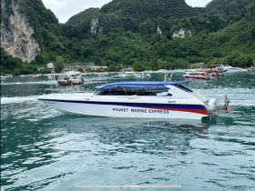 A sleek speedboat, the Phuket Marine Express, glides through the turquoise waters, surrounded by lush green mountains — a perfect representation of Thailand's stunning marine scenery.