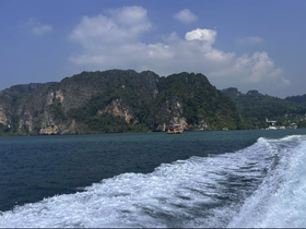 A stunning view of lush green islands and a distant boat cruising through clear waters, showcasing the beauty of the coastline.