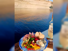 A beautifully arranged charcuterie platter with fresh vegetables and a glass of wine, perfect for enjoying while cruising on the water.