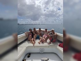 A lively group enjoys a day on the water, relaxing on the deck of a boat under a beautiful sky — perfect for summer adventures and celebrations.