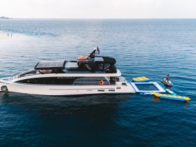 A stunning aerial view of a luxurious yacht anchored in serene waters, showcasing its sleek design and surrounding water toys, perfect for a day of fun on the sea.