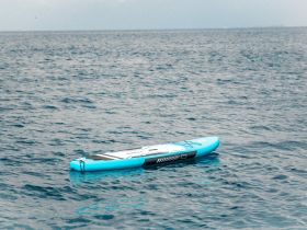 A vibrant blue paddleboard floats serenely on calm waters, perfect for a day of fun and adventure on the sea.