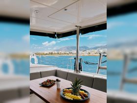 A beautifully arranged fruit platter and snacks set on a dining table inside a boat, offering a perfect touch for a relaxing day on the water.