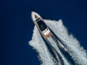 A stunning aerial view of a speedboat cutting through deep blue waters, showcasing its sleek design and dynamic movement.