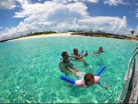 A joyful family enjoys a day of swimming in crystal-clear waters, creating unforgettable memories at a beautiful beach destination.