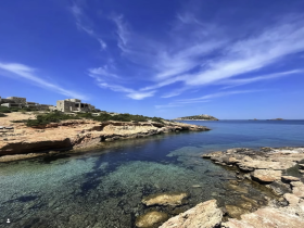 A stunning view of a serene coastline with crystal-clear waters and rocky formations, perfect for showcasing the natural beauty of island destinations.