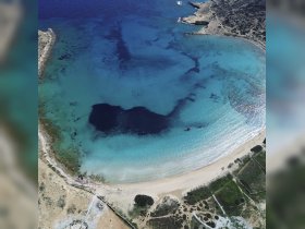 A stunning aerial view of a tranquil coastline with crystal-clear waters, showcasing the natural beauty of the area — perfect for exploring by boat.