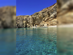 A stunning view of a secluded beach with crystal-clear waters and rocky cliffs, perfect for a tranquil getaway or eco tour.