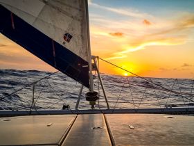 A stunning sunset view from the deck of a sailing catamaran, capturing the beauty of the ocean and the tranquility of the moment.