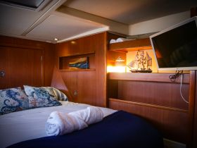 Cozy interior cabin of a boat featuring a comfortable bed, decorative pillows, and a charming ship model, perfect for relaxing during your nautical adventures.